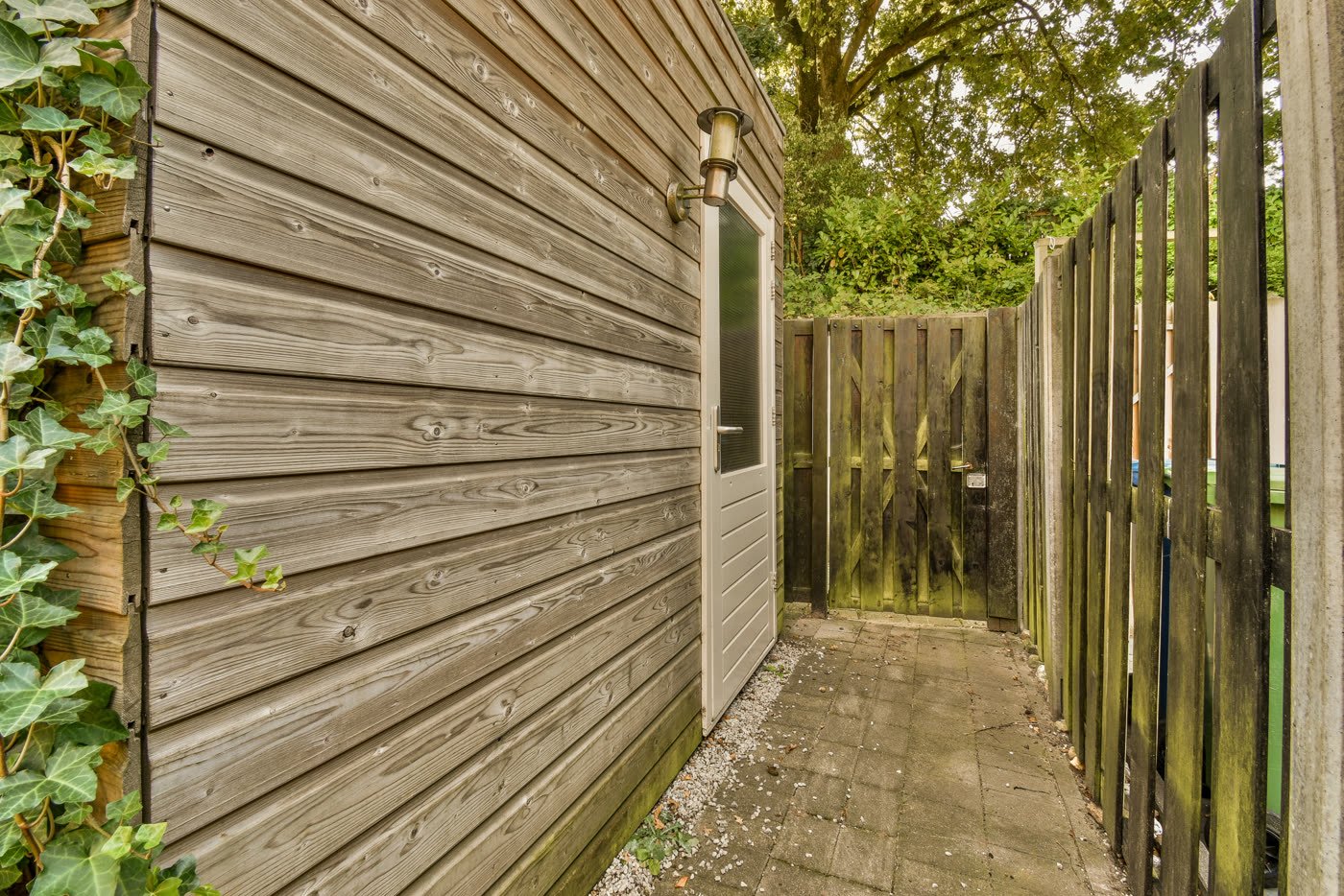 A narrow side gate and paved side yard leading to a back garden.